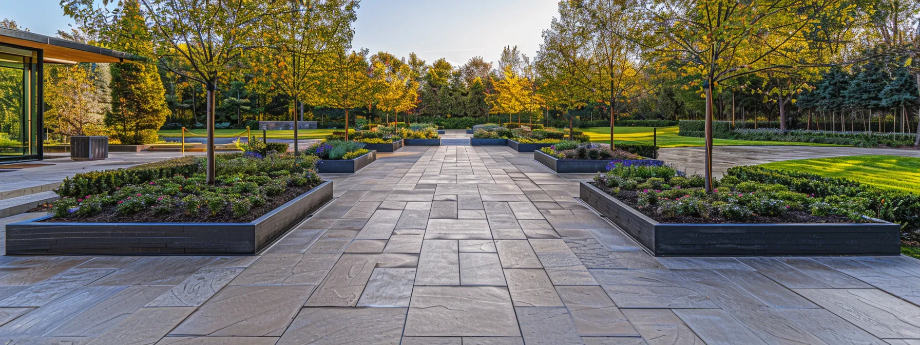 a vast expanse of 2000 sq ft freshly laid pavers, meticulously planned and installed with precision, featuring elegant stamped concrete accents and a functional french drain seamlessly integrated into the design.